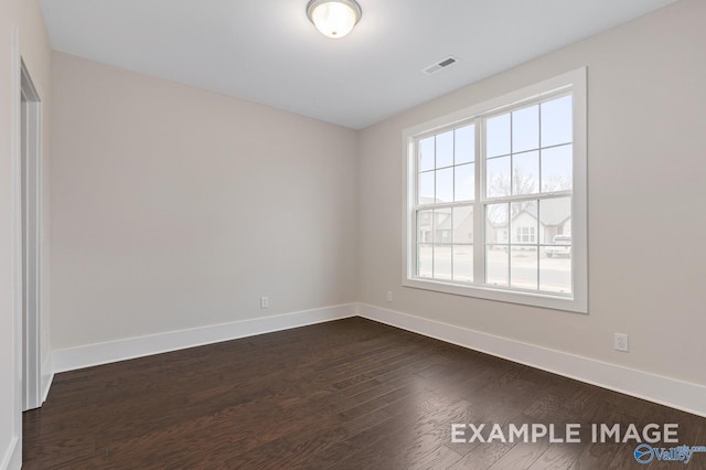 empty room featuring baseboards, visible vents, and dark wood-type flooring