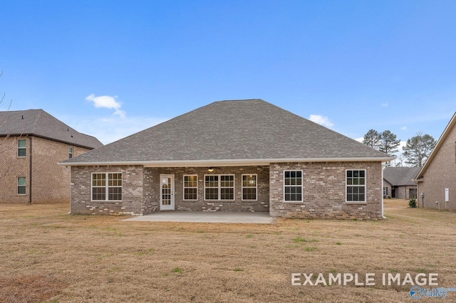 back of property with a yard, brick siding, a patio, and roof with shingles