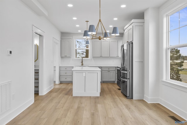 kitchen with a center island, a wealth of natural light, visible vents, and freestanding refrigerator