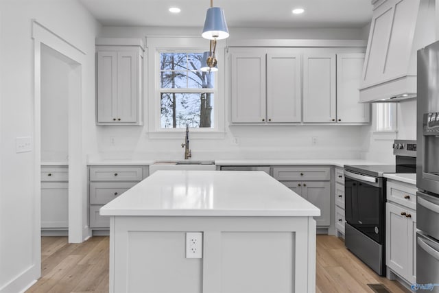 kitchen with light countertops, a sink, stainless steel appliances, and light wood-style flooring