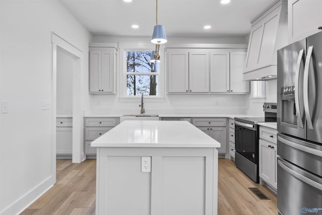 kitchen with light countertops, stainless steel appliances, hanging light fixtures, a sink, and visible vents