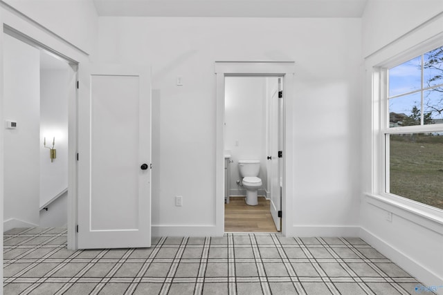 unfurnished bedroom featuring ensuite bath and baseboards