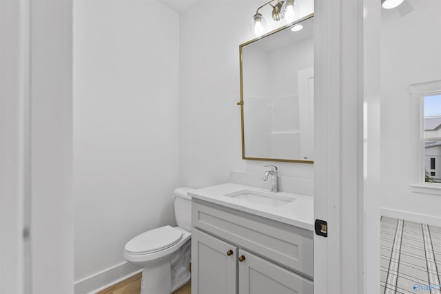 bathroom with baseboards, toilet, and vanity