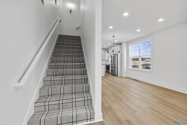 stairway featuring recessed lighting, baseboards, and wood finished floors