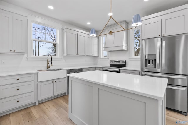 kitchen with light countertops, a sink, stainless steel appliances, and light wood-style floors