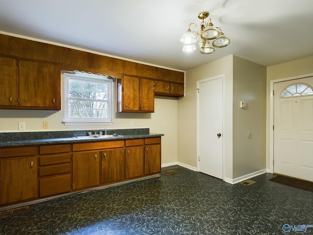 4227 Keith Dr NW, Huntsville, AL 35810 - kitchen with dark flooring, a sink, dark countertops, a chandelier, and baseboards
