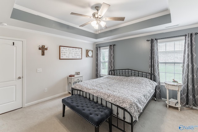 carpeted bedroom featuring a raised ceiling, multiple windows, ceiling fan, and ornamental molding