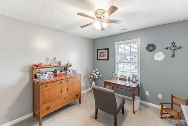 carpeted office space featuring ceiling fan and a textured ceiling