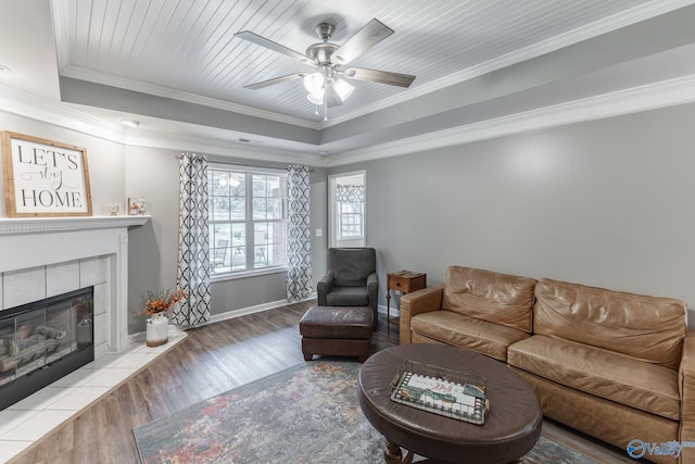 living room featuring hardwood / wood-style floors, a fireplace, ceiling fan, and crown molding