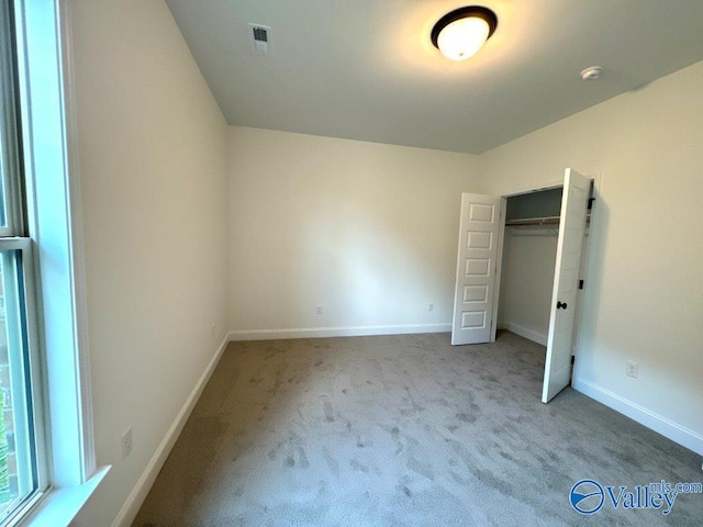 unfurnished bedroom featuring light colored carpet and a closet