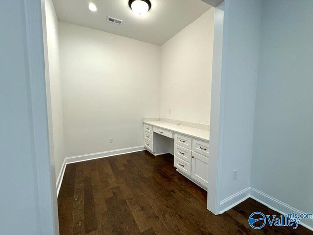 unfurnished office with dark hardwood / wood-style flooring and built in desk