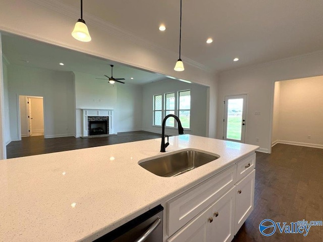 kitchen with sink, a premium fireplace, light stone countertops, white cabinets, and decorative light fixtures