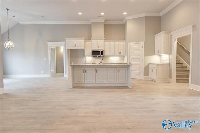 17401 Stonegate Dr, Athens, AL 35613 - kitchen featuring stainless steel microwave, crown molding, backsplash, light wood-style flooring, and baseboards