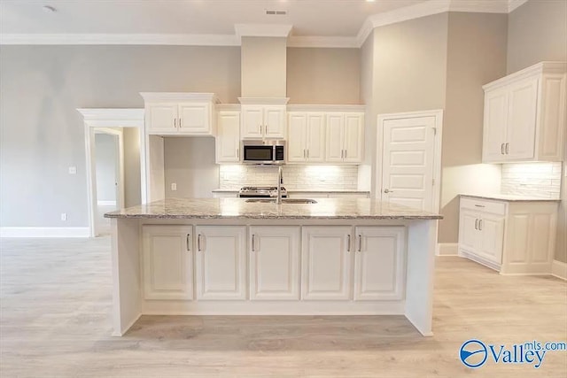 17401 Stonegate Dr, Athens, AL 35613 - kitchen featuring stainless steel microwave, a sink, ornamental molding, decorative backsplash, and light stone counters
