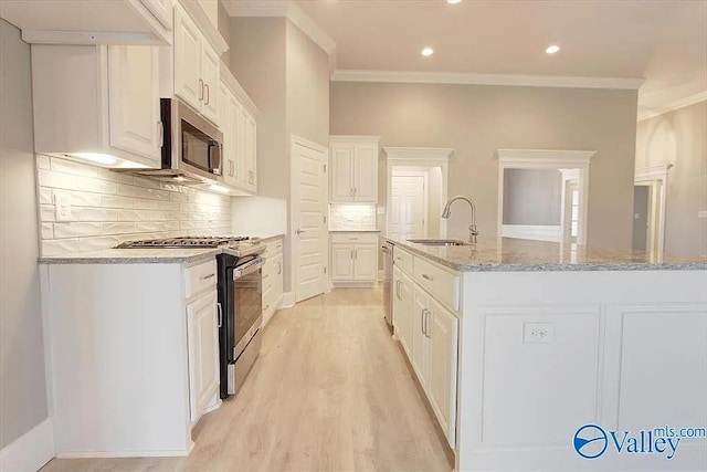 17401 Stonegate Dr, Athens, AL 35613 - kitchen with stainless steel appliances, a sink, ornamental molding, light wood-type flooring, and backsplash
