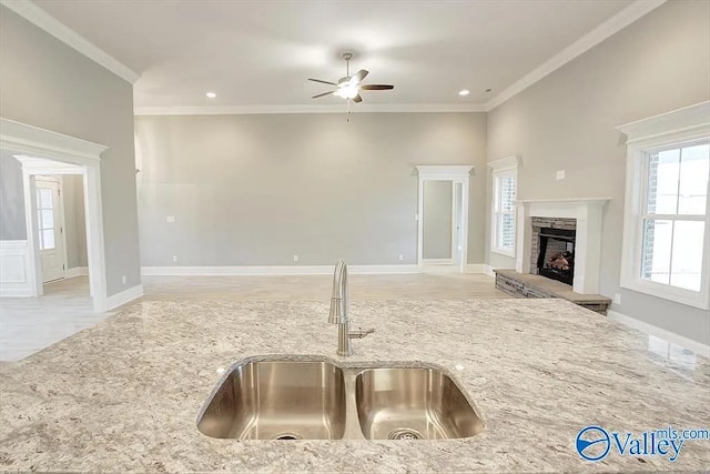 17401 Stonegate Dr, Athens, AL 35613 - kitchen with a sink, ceiling fan, crown molding, light stone countertops, and a stone fireplace
