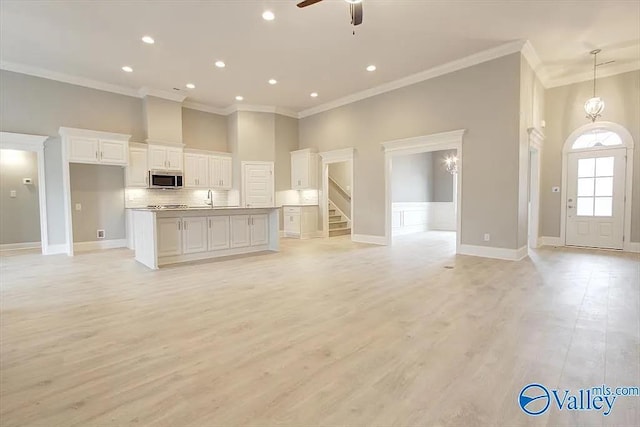 17401 Stonegate Dr, Athens, AL 35613 - kitchen featuring stainless steel microwave, open floor plan, crown molding, a ceiling fan, and white cabinets