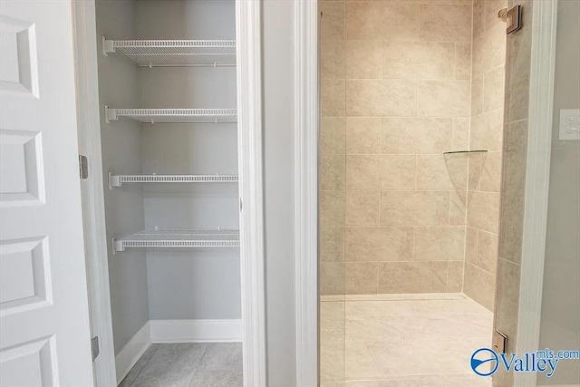 17401 Stonegate Dr, Athens, AL 35613 - bathroom featuring tiled shower, tile patterned floors, a walk in closet, and baseboards