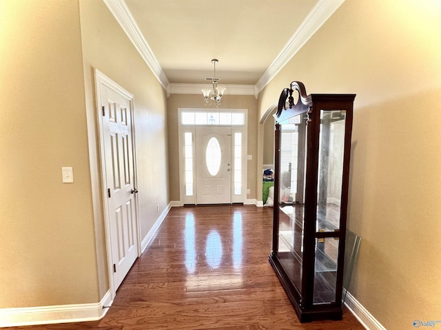 entrance foyer featuring dark wood-style floors, ornamental molding, baseboards, and an inviting chandelier