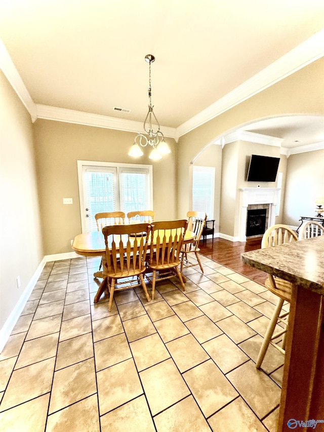 dining area featuring crown molding, visible vents, a fireplace, and baseboards