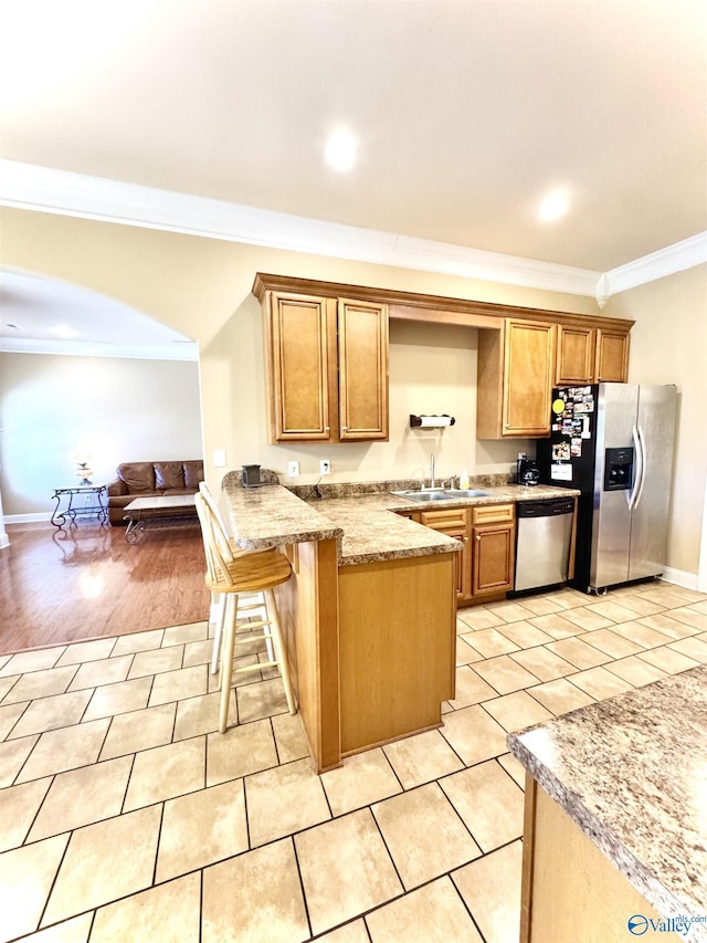 kitchen featuring light tile patterned floors, appliances with stainless steel finishes, ornamental molding, a peninsula, and a sink