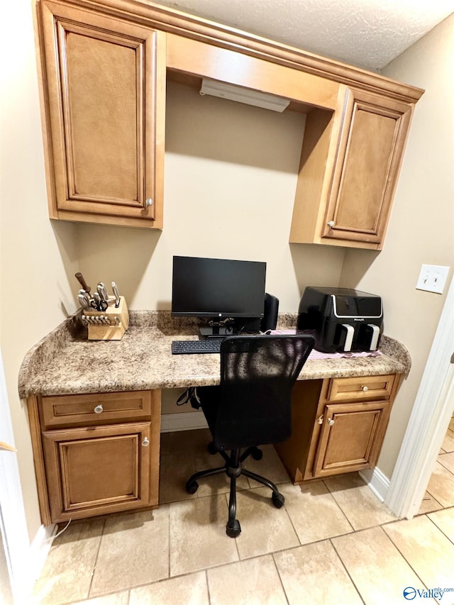 office area with built in desk, baseboards, and a textured ceiling