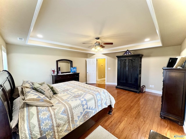 bedroom featuring a raised ceiling, visible vents, baseboards, and light wood finished floors