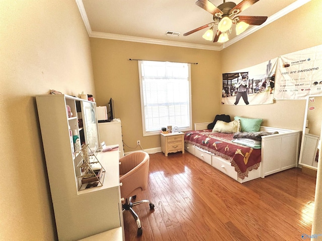 bedroom featuring ceiling fan, hardwood / wood-style flooring, visible vents, baseboards, and crown molding