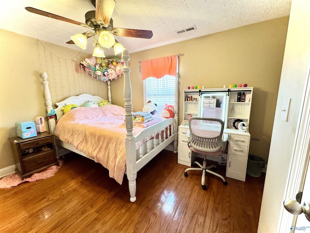 bedroom featuring a textured ceiling, wood finished floors, visible vents, and a ceiling fan