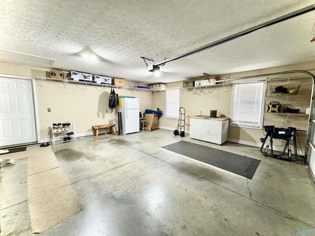 garage with a garage door opener, freestanding refrigerator, and baseboards