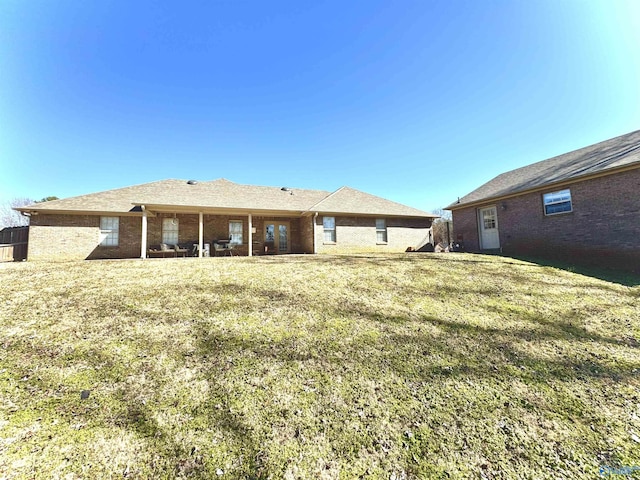 back of property with a lawn and brick siding