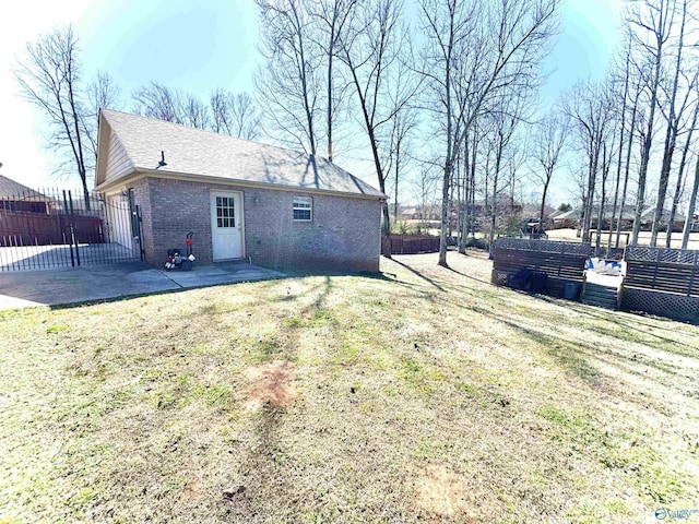 back of house featuring a yard, a patio, brick siding, and fence