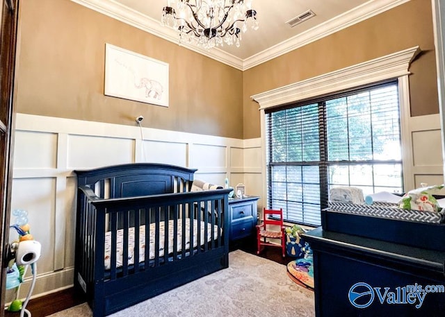 bedroom featuring crown molding, a chandelier, a nursery area, and wood-type flooring