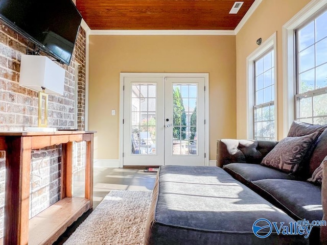 living room featuring a healthy amount of sunlight, brick wall, french doors, and ornamental molding