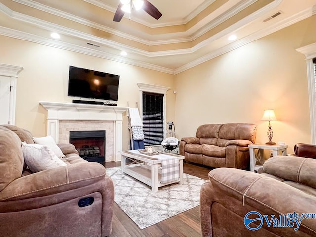 living room with crown molding, wood-type flooring, ceiling fan, and a raised ceiling