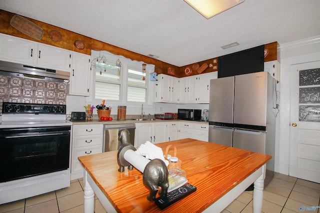 kitchen with appliances with stainless steel finishes, sink, light tile patterned floors, and white cabinets