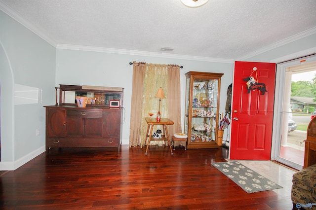 entrance foyer with dark wood-type flooring, ornamental molding, and a textured ceiling