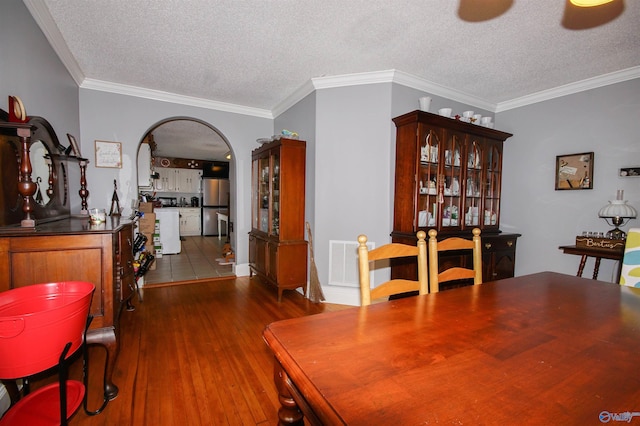 dining room featuring crown molding, dark wood-type flooring, and a textured ceiling