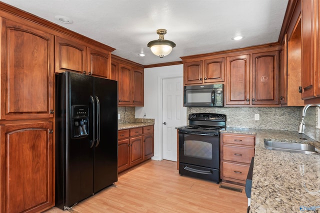 kitchen featuring light hardwood / wood-style floors, tasteful backsplash, black appliances, and sink