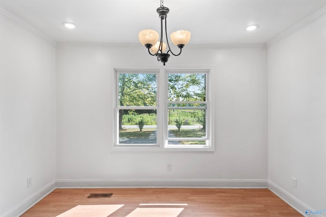 spare room featuring an inviting chandelier, light hardwood / wood-style flooring, and crown molding