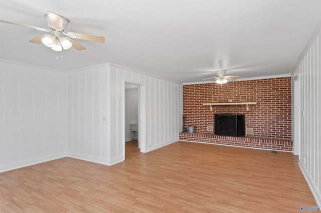 unfurnished living room with light hardwood / wood-style flooring, ornamental molding, brick wall, a brick fireplace, and ceiling fan