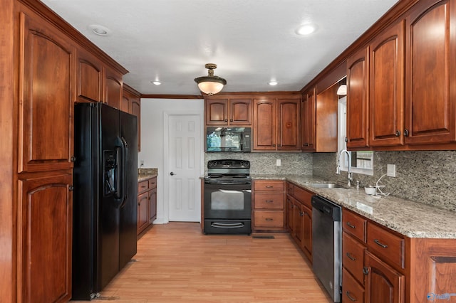 kitchen featuring black appliances, sink, light hardwood / wood-style floors, light stone counters, and decorative backsplash