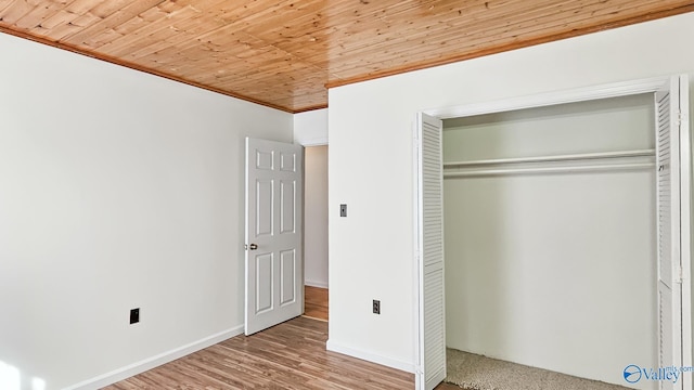 unfurnished bedroom featuring wood finished floors, baseboards, crown molding, a closet, and wooden ceiling