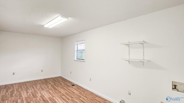 spare room with light wood finished floors, visible vents, a textured ceiling, and baseboards