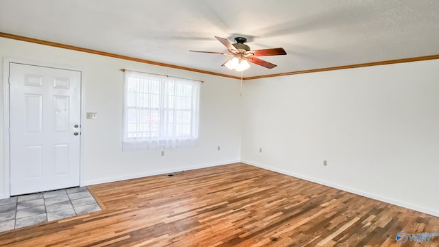 foyer entrance with visible vents, crown molding, baseboards, ceiling fan, and wood finished floors