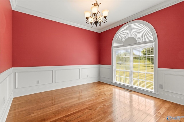 unfurnished room with a chandelier, a wainscoted wall, wood-type flooring, and ornamental molding