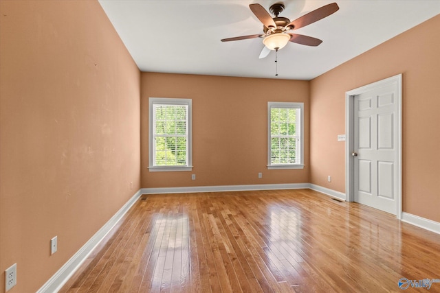 empty room with plenty of natural light, light wood-type flooring, a ceiling fan, and baseboards