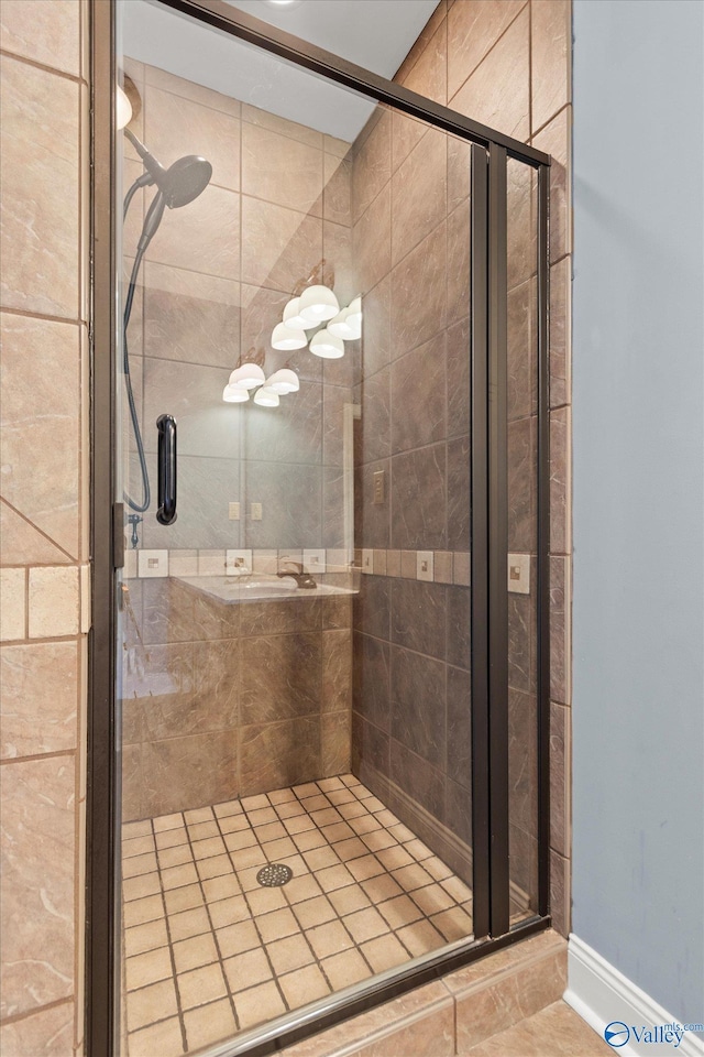 bathroom featuring a shower stall, baseboards, and tile patterned flooring