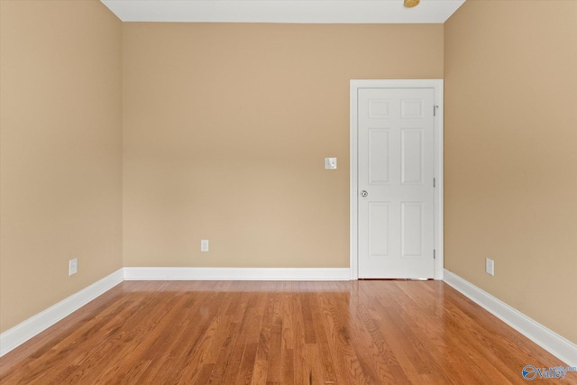 spare room with baseboards and light wood-style floors