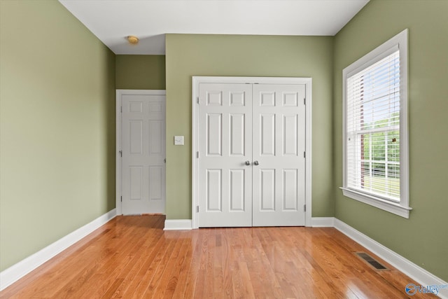 unfurnished bedroom featuring light wood-style flooring, a closet, and baseboards